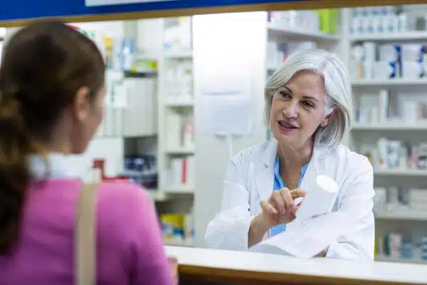 Female pharmacist at window talking to woman