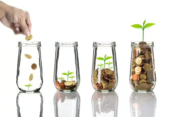 Hand putting in coins in glass jars