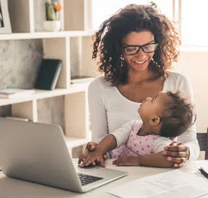 Young mom with baby sitting at a laptop computer