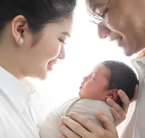 A mom and dad smile down on their newborn baby